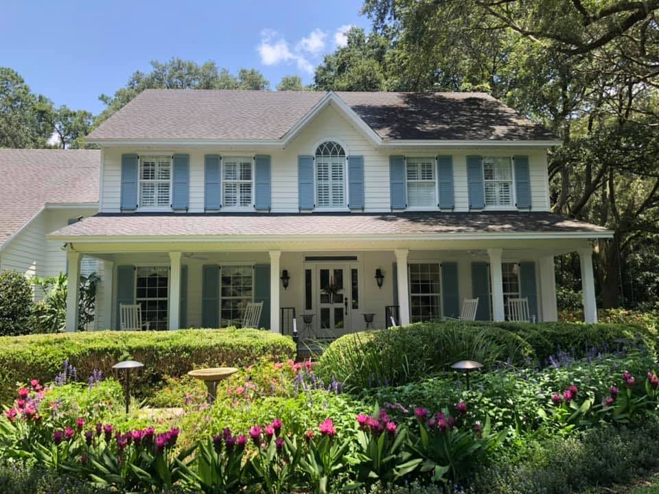 Beautifully painted Gainesville home with light blue shutters and a wraparound porch by A+ Painting and Repair